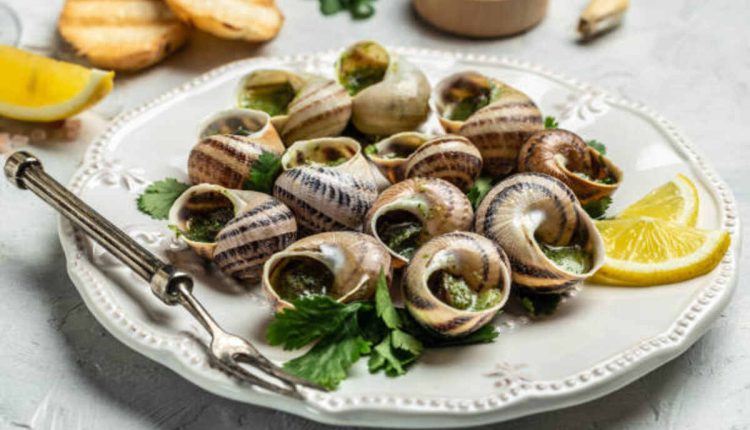 A plate of escargo, garnished with herbs and garlic butter